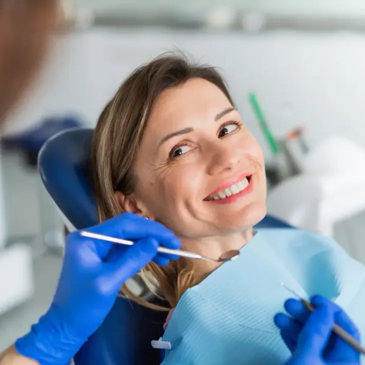 A patient smiling up at her dentist during a checkup