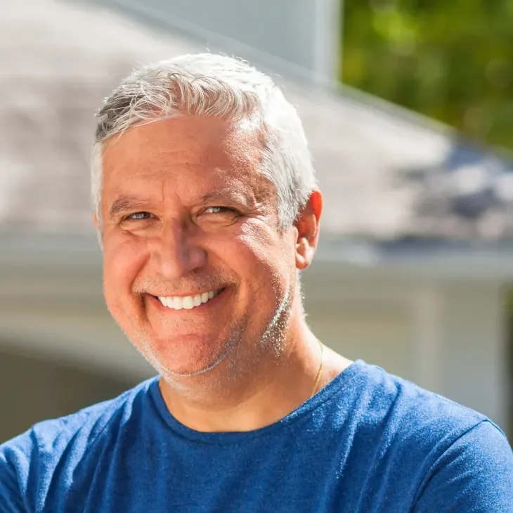 An older man smiling confidently outdoors