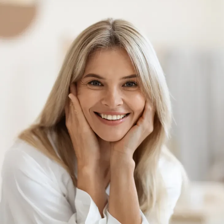 A smiling middle-aged woman resting her chin on her hands