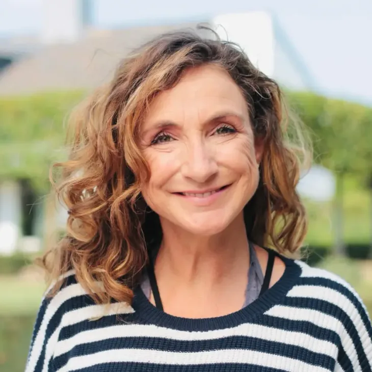 A smiling woman with curly hair outdoors
