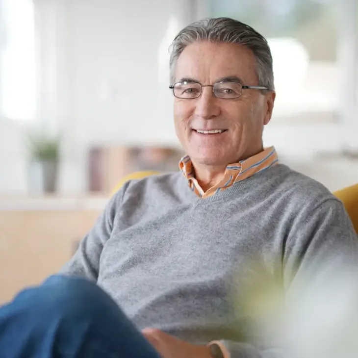 A silver-haired man relaxing at home and smiling