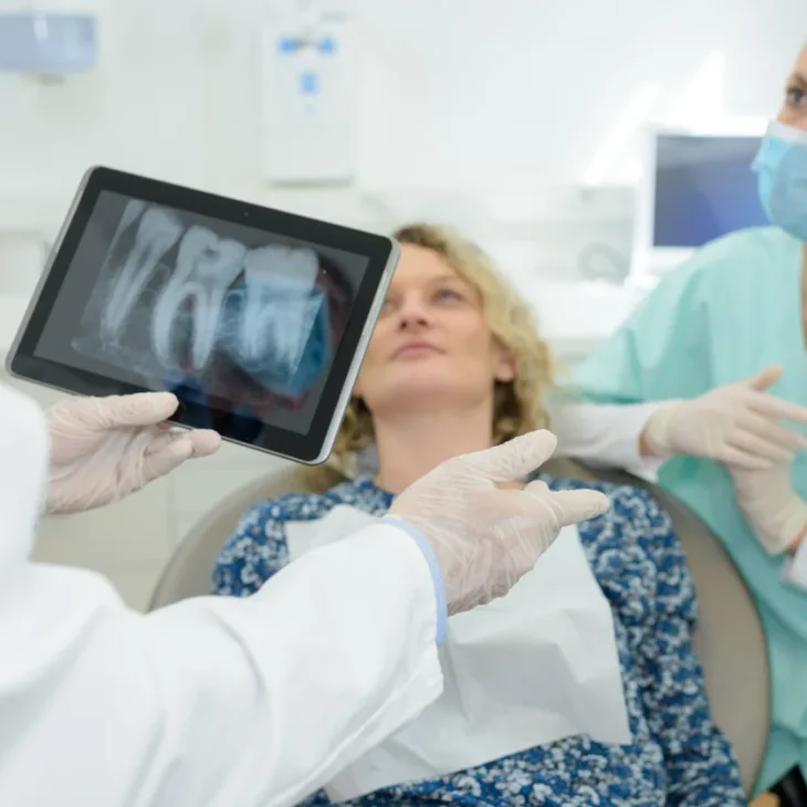 A dentist showing a patient her X-ray on a tablet