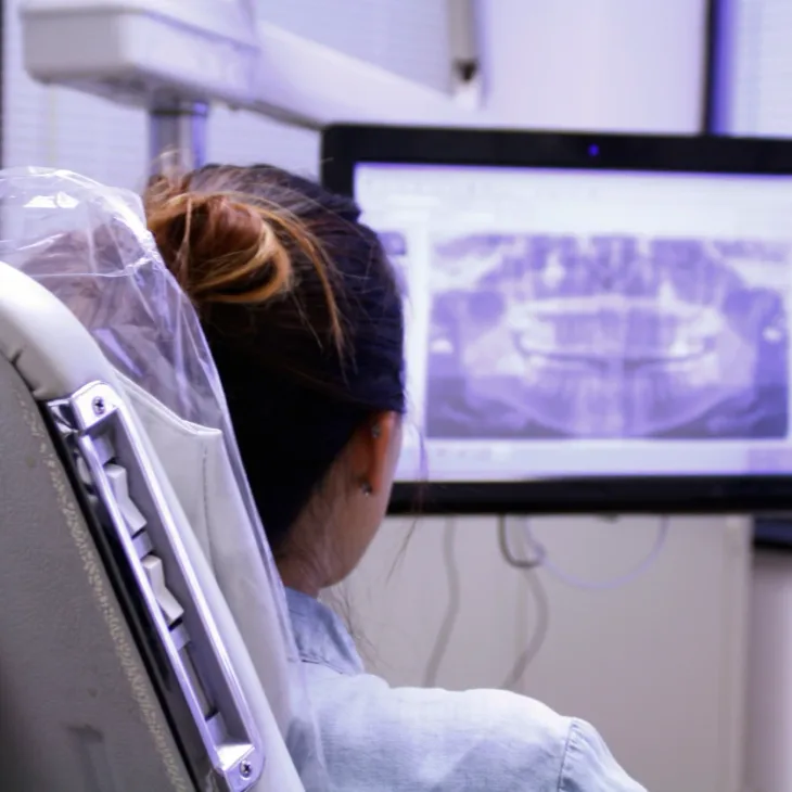 A dental assistant reviewing a panoramic X-ray on screen