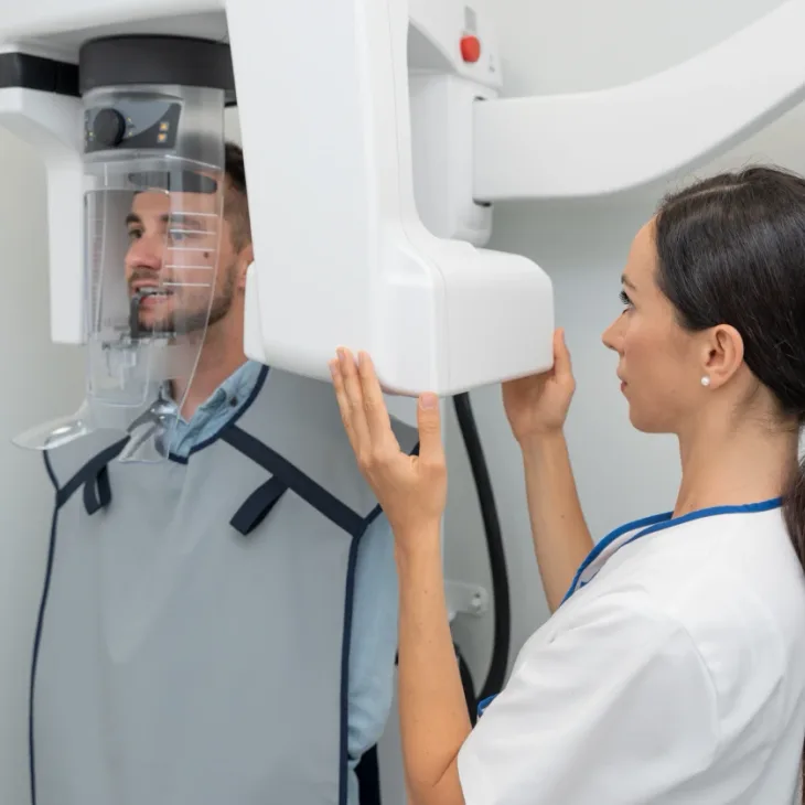 A man being positioned in an upright panoramic X-ray scanner