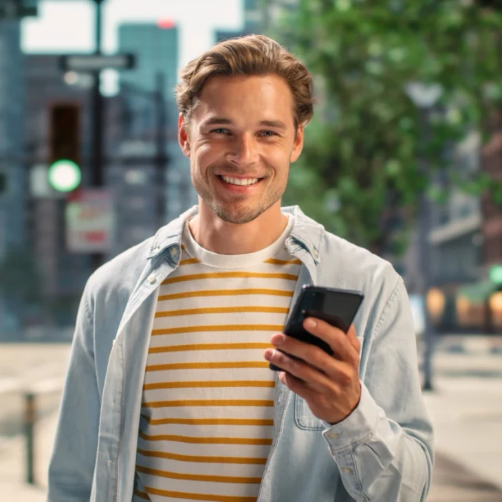 A patient smiling on a city street, phone in hand