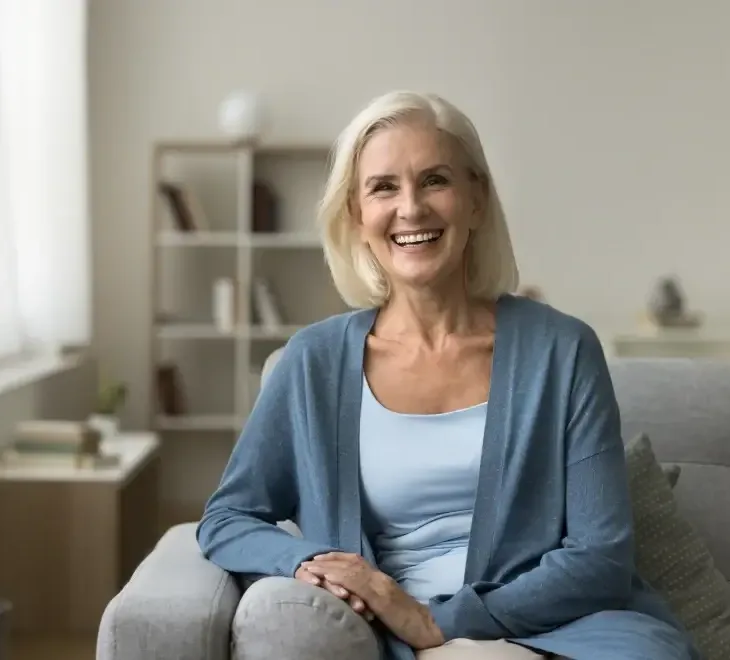 A smiling silver-haired woman seated at home