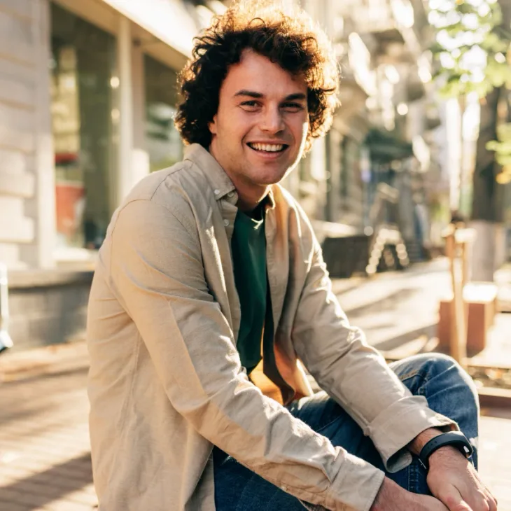 A smiling man sitting outside a shopfront