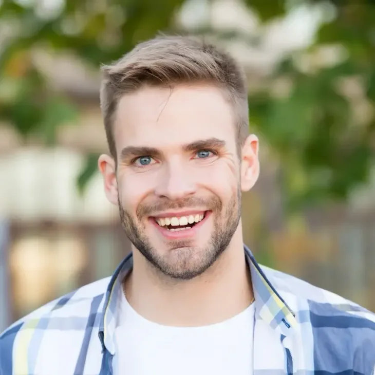A smiling man outdoors in a checked shirt