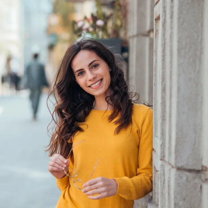 A smiling woman in a yellow top on a city street
