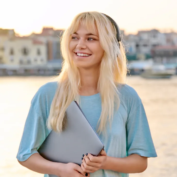 A smiling woman holding a folder outdoors