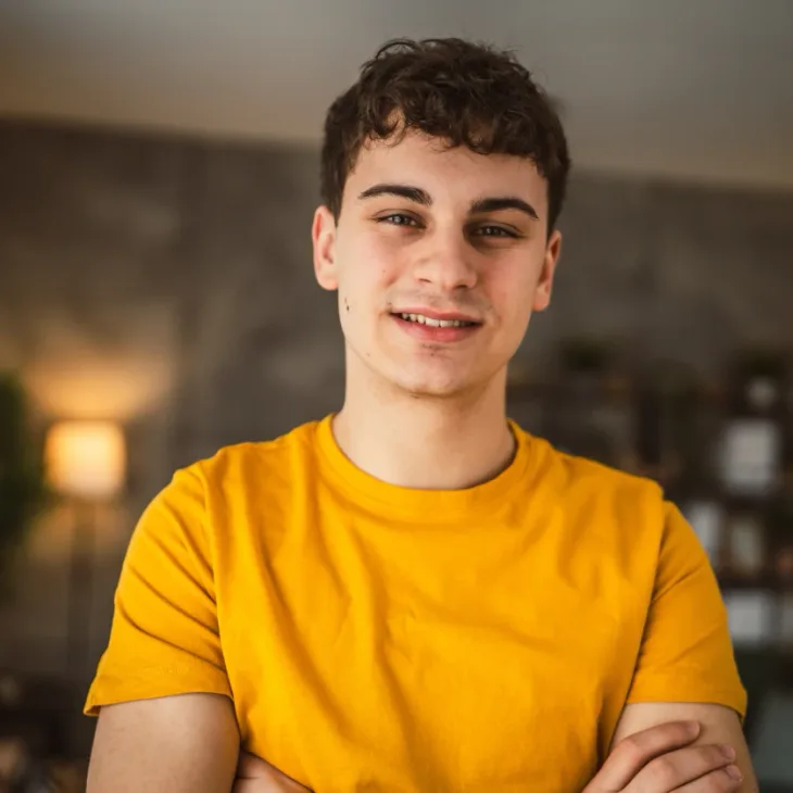 A smiling teenage boy in a yellow t-shirt