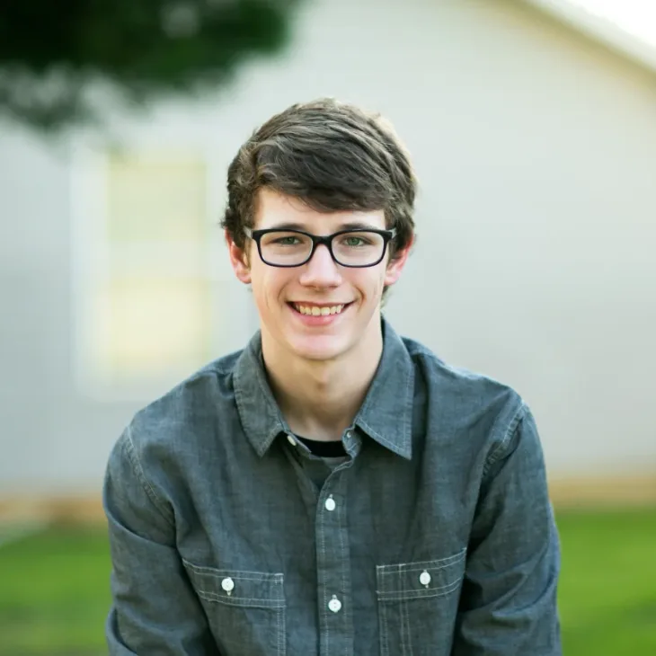 A smiling young man in glasses outdoors