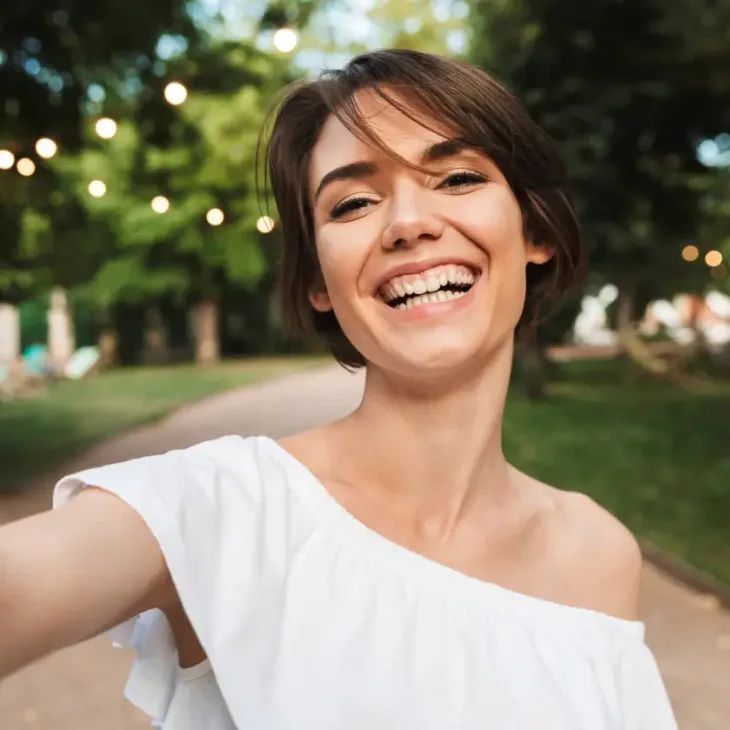 A laughing woman outdoors in a white top