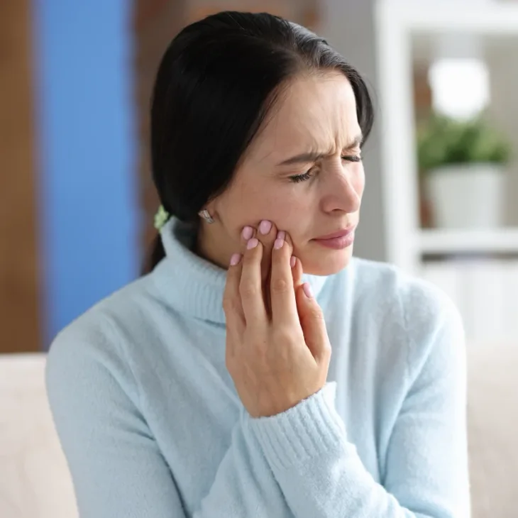 A woman holding her cheek in pain