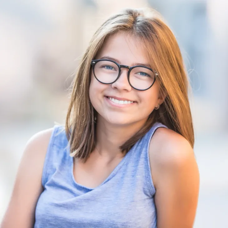 A smiling teenage girl in glasses