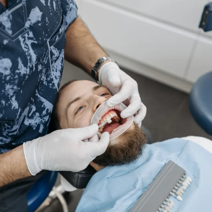 A dentist matching veneer shades for a patient in the chair