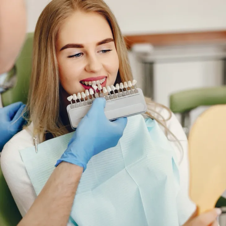 A woman comparing veneer shades held up to her smile